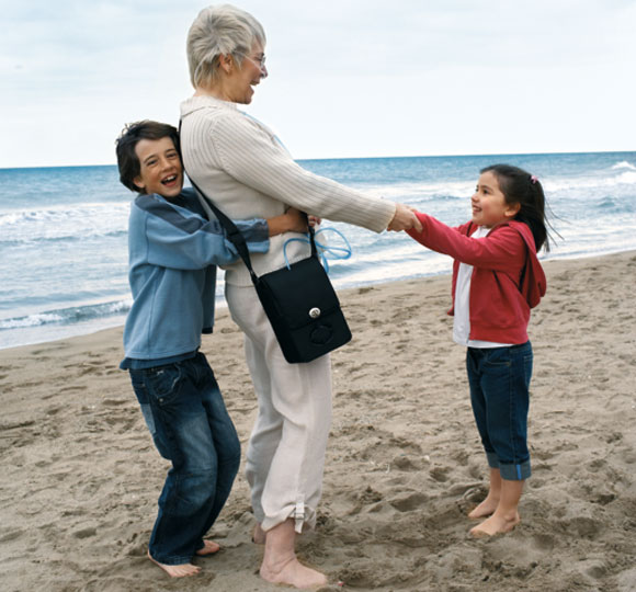 Dame mit Kindern am Strand mit mobilem Sauerstoffkonzentrator